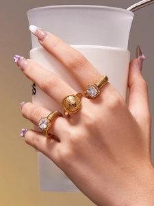 Détail de trois bagues dorées avec zircon carré et texture sur une main de femme