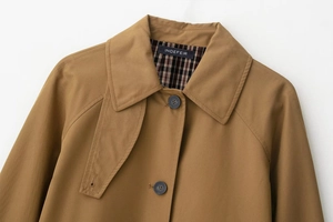 Detailed macro view of camel trench coat twill fabric with refined button and raglan sleeve