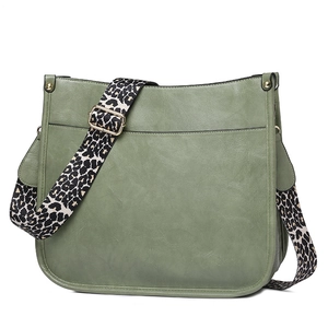 Green faux leather crossbody bag detail featuring a wide leopard print shoulder strap