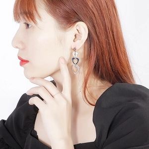 Boucles d'oreilles pendantes cœur argentées multicouches portées par un mannequin femme