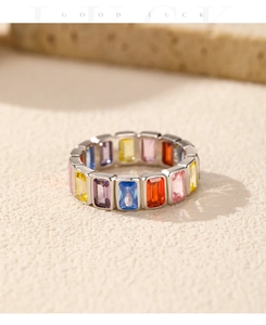 Macro shot of silver ring with colorful baguette cut gemstones on beige stone