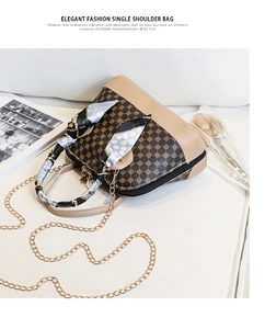 Detail of floral shell crossbody bag with golden chain and decorative silk scarf strap