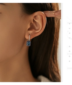 Dettaglio dell'orecchino in argento s925 con gemma blu e smalto sull'orecchio