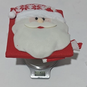 Detailmessung des Gewichts einer roten Weihnachtsmann-Stuhlhülle aus Stoff auf einer Digitalwaage