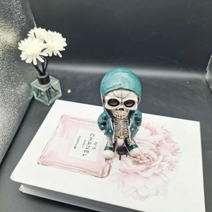 Close-up of green hoodie skeleton figurine on a decorative book with flowers