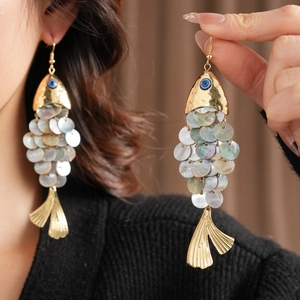 Detailed macro view of fish-shaped earrings with golden scales and blue eye accents