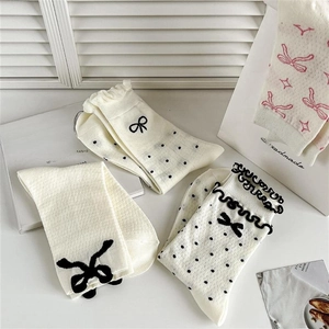 Detailed close-up of cream socks with black bows, polka dots, and delicate ruffled cuffs