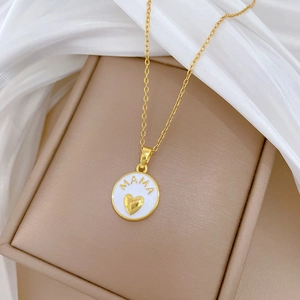 Detail of gold MAMA necklace with white heart pendant on elegant silk background