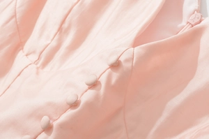 Macro shot of pink dress with fabric-covered buttons and fine texture detail