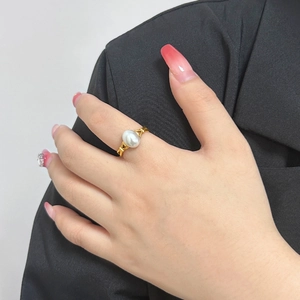 Elegante anello in acciaio dorato con perla barocca bianca indossato da modella su nero