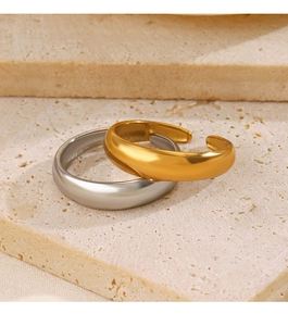 Close-up of gold and silver polished curved open rings on a natural stone surface