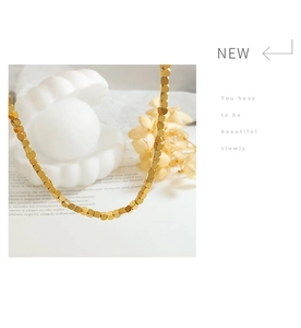 Close-up of minimalist gold square cube bead necklace set on a luxury white porcelain tray