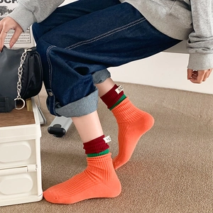 Close-up of orange cotton crew sock with ribbed texture and striped cuff detail