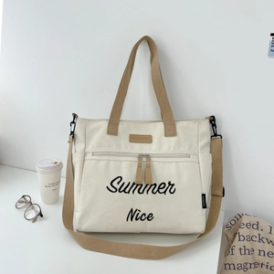 Detail of canvas tote bag featuring Summer Nice embroidery and adjustable shoulder strap
