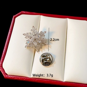Macro view of a 2.2cm silver snowflake brooch with crystals in a gift box