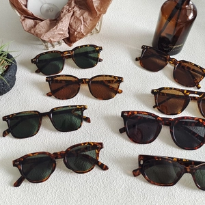 Flat lay of multiple leopard print sunglasses with various colored lenses on white texture