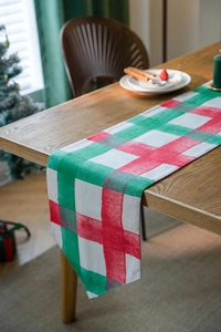 Close-up of red and green plaid Christmas table runner on a wooden dining table