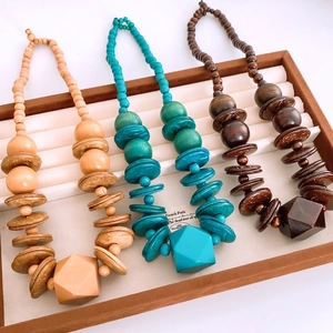 Detailed view of ethnic style beaded necklaces with geometric wooden pendants in three colors