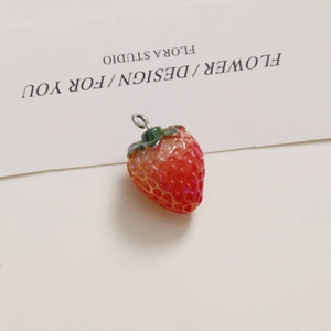 Macro view of realistic red resin strawberry pendant with green leaf and silver ring