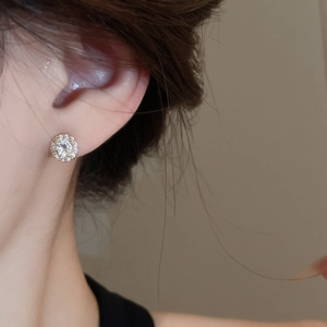 Detailed view of silver zircon halo stud earrings worn on ear with sparkling round crystals
