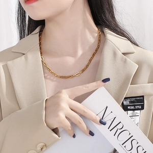 Minimalist gold titanium steel geometric link necklace worn by a fashion model in soft light