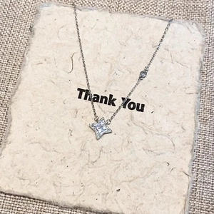 Elegant silver four-pointed star pendant necklace with sparkling zircon on beige paper