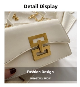 Close-up of white leather crossbody bag with gold interlocking buckle and chain strap