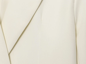 Gros plan sur le tissu tissé blanc ivoire et les coutures du revers du blazer croisé