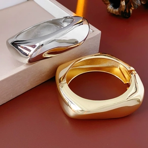 Macro view of minimalist irregular metal bangles in polished gold and silver finishes