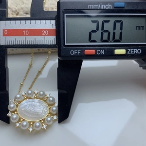 Macro shot of Guadalupe shell pendant measuring 26.0mm with golden frame and pearls