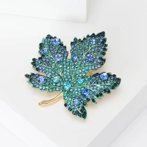 Macro shot of high-end maple leaf brooch with vibrant blue and cyan rhinestones
