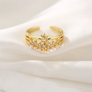Détail d'une bague couronne dorée avec perles blanches et zircons sur fond de soie