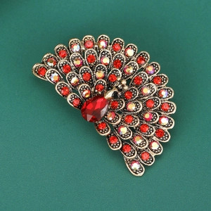 Macro shot of peacock brooch featuring red rhinestones and vintage gold metal finish