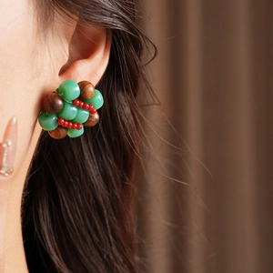 Detail of handmade beaded cluster earring with green and red accents on model ear