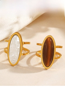 Detailed macro view of dual-band gold rings featuring marble and tiger eye stone inlay
