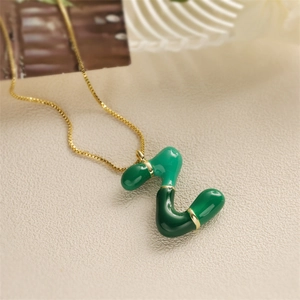 Dettaglio macro del ciondolo lettera Z verde con bordo dorato e catenina sottile d'oro