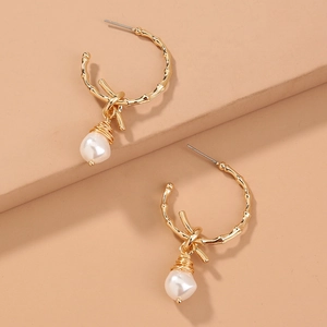 Bamboo-shaped golden hoop earrings with elegant baroque imitation pearls on pink steps
