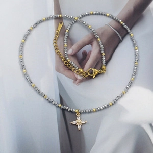 Detail of beaded necklace featuring dark grey faceted crystals and a golden starburst pendant
