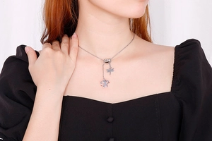 Détail d'un collier coeur argenté avec pendentifs libellule et papillon sur modèle