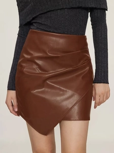 Détail d'une jupe froncée en cuir PU marron avec ourlet asymétrique et plis à la taille