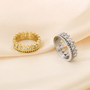 Detail of gold and silver crown rings with clear crystals on beige silk fabric