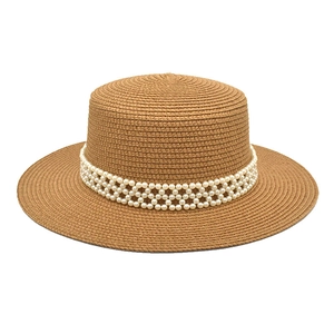 Detail of flat-top straw hat with elegant white faux pearl woven headband trim