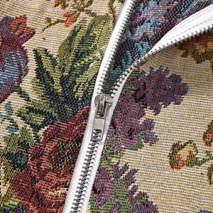 Nahaufnahme eines Silbermetallreißverschlusses auf floralem Jacquardstoff mit Stickerei