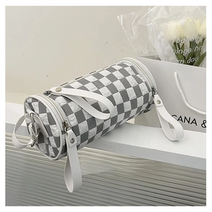 Detail of grey checkerboard cylinder bag with white handles and silver hardware on a podium