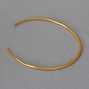 Detail of minimalist wavy gold-plated brass choker with irregular open-ended design