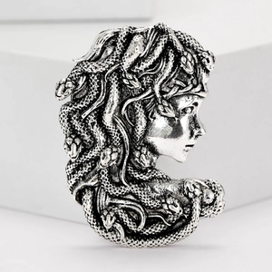 Close-up of silver Medusa head brooch with intricate snake hair texture detail