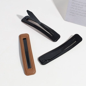 Close-up of brown and black PU leather hair clips with vintage wrinkled texture and metal base
