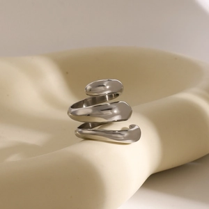 Macro shot of silver spiral three-layer ring on a minimalist cream display stand