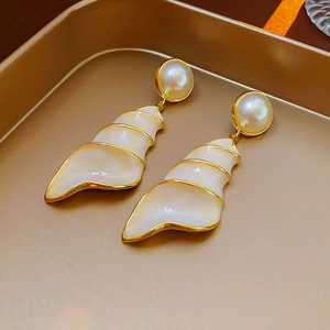 Close-up of vintage shell earrings with pearl studs on a gold tray background