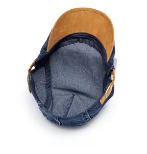 Internal view of washed denim newsboy cap with brown suede strap and metal buckle